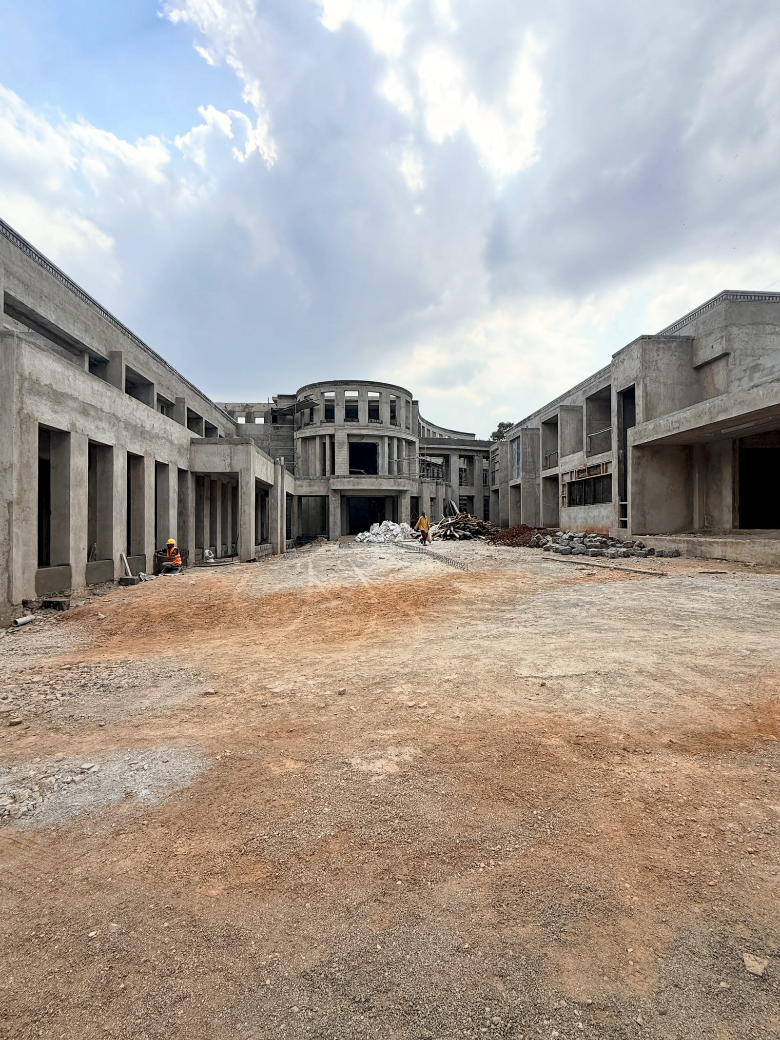 The hotel courtyard at plaster stage, colonnaded wings on either side framing the curved central block