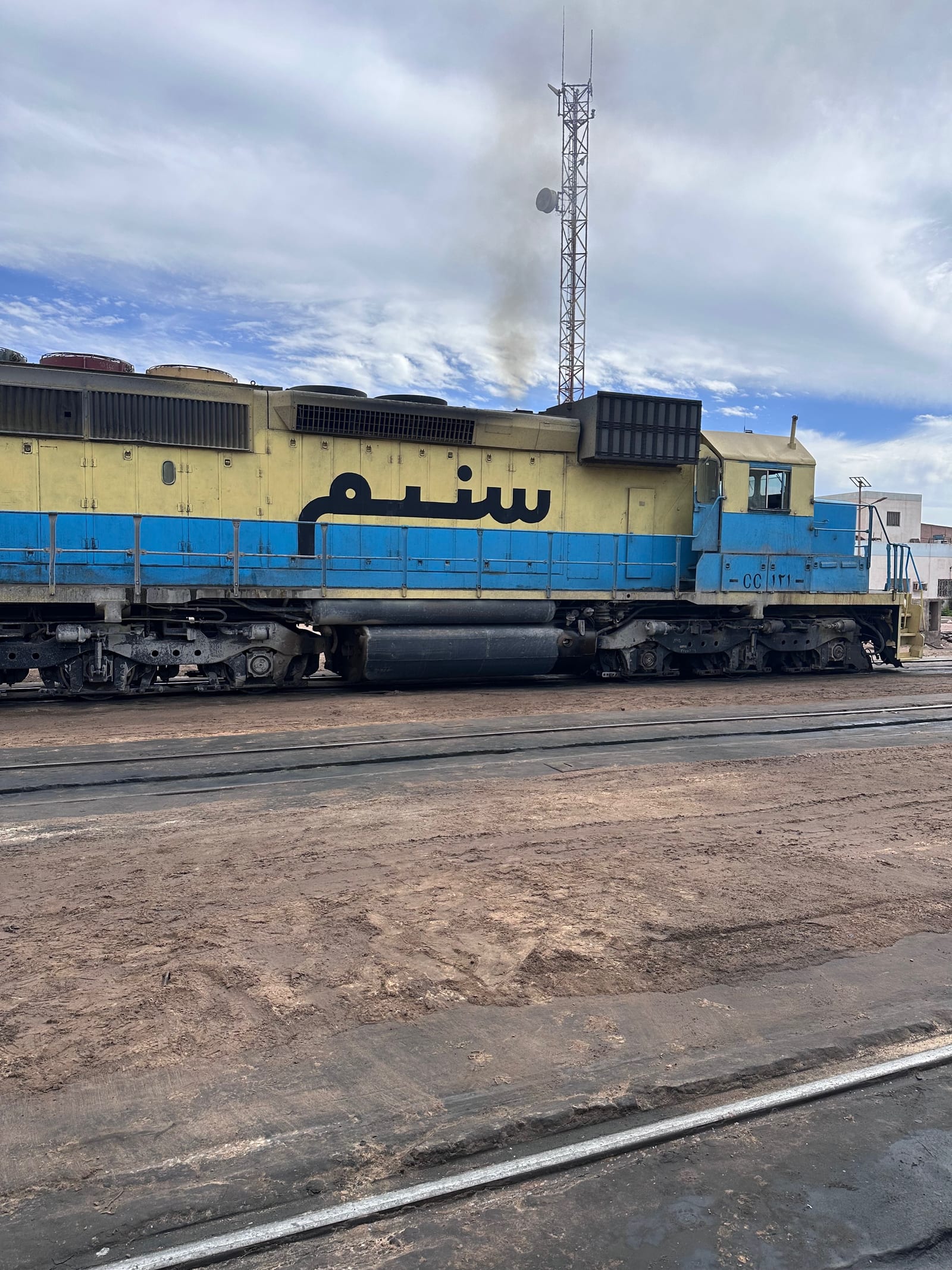 An SNIM diesel locomotive in yellow and blue livery at the Nouadhibou railway yard on the Mauritanian iron ore line