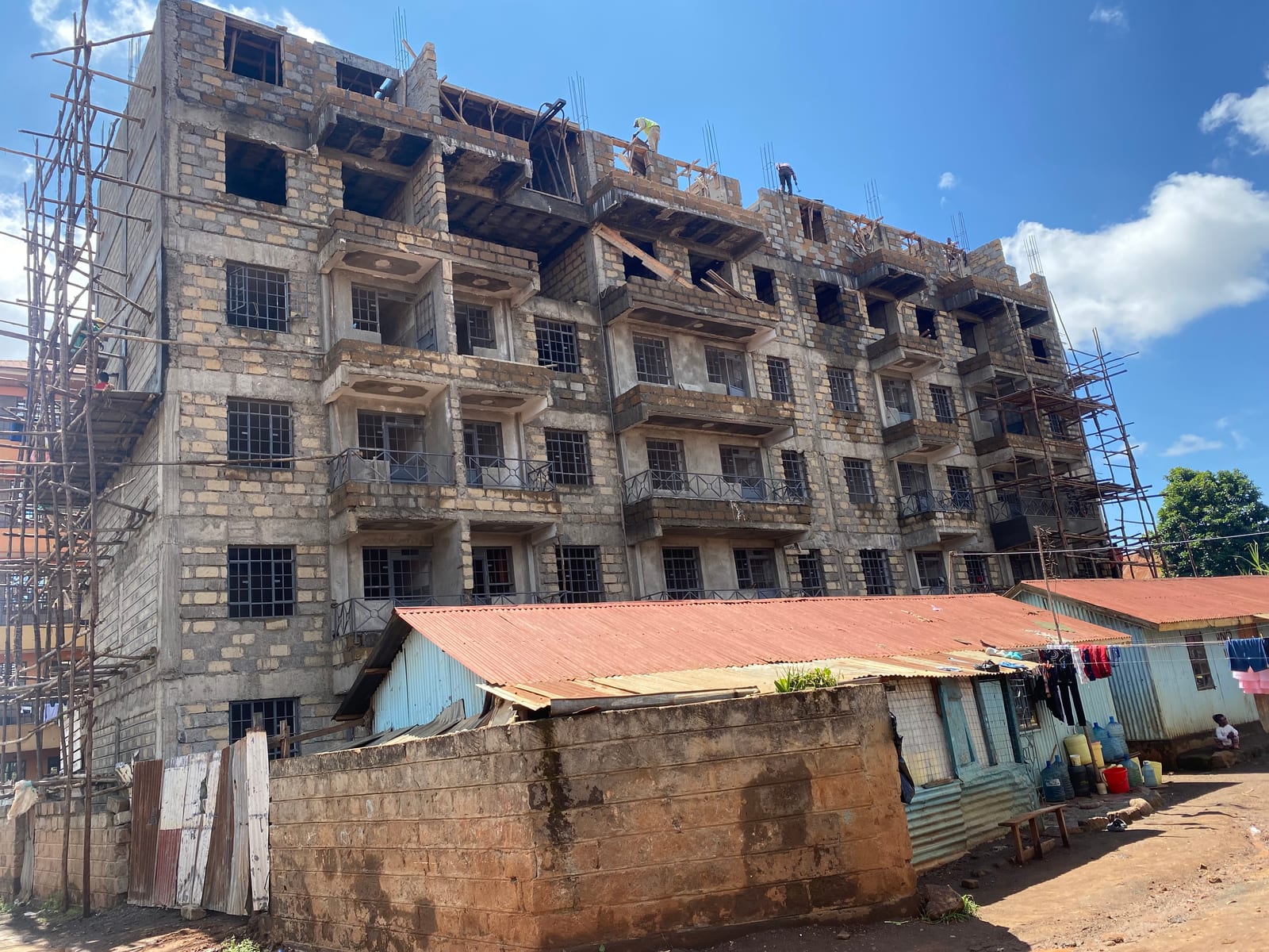 The load-bearing stone-masonry superstructure of the ACK Trinity Muthua apartments, cast concrete balconies and workers on the top slab